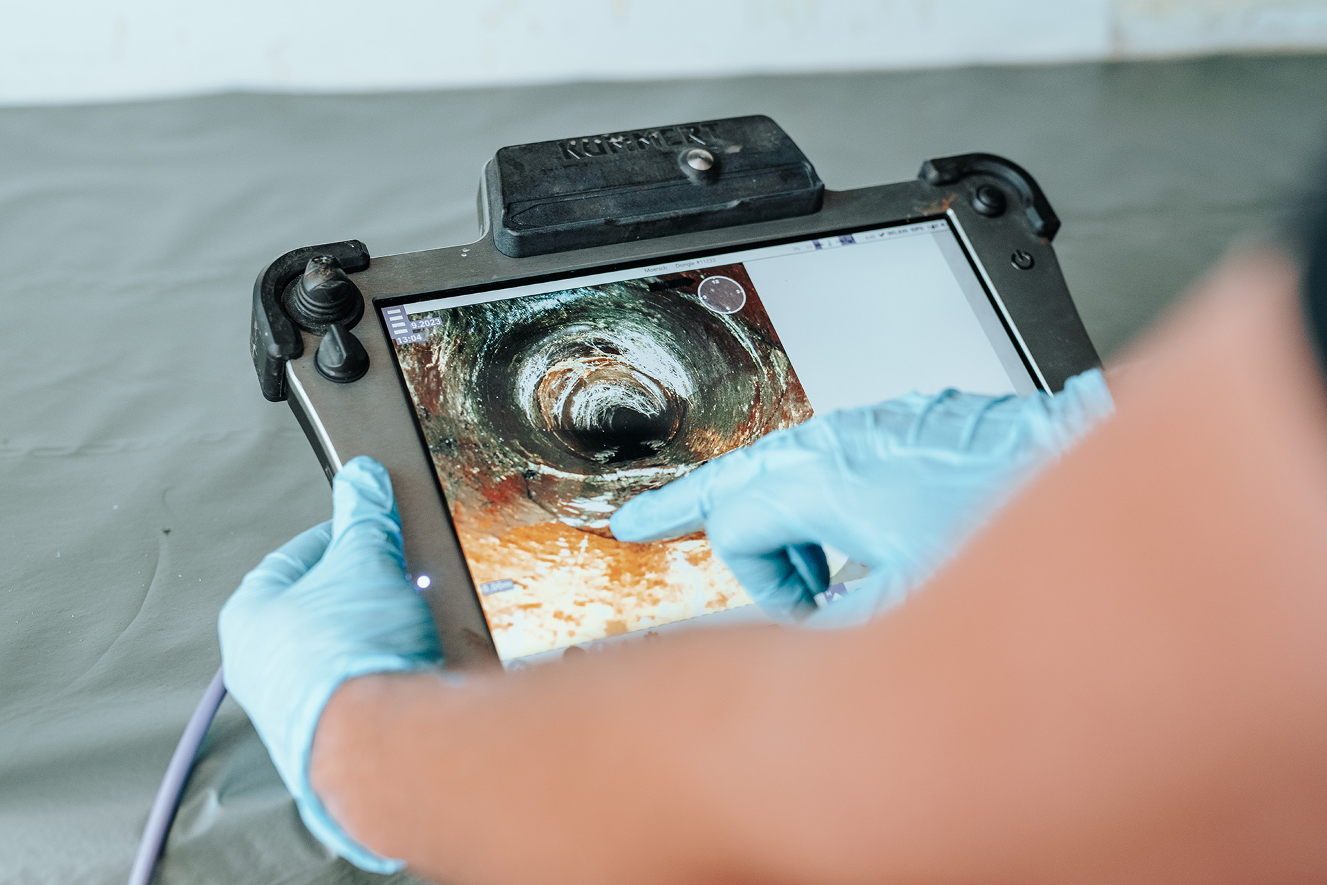Mitarbeiter von Moersch Kanal zeigt auf einem Tablett eine Kameraführung durch einen Kanal.